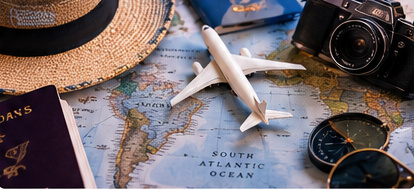 Mapa-múndi com avião em miniatura, passaporte, câmera fotográfica e acessórios de viagem, representando turismo e viagens internacionais.